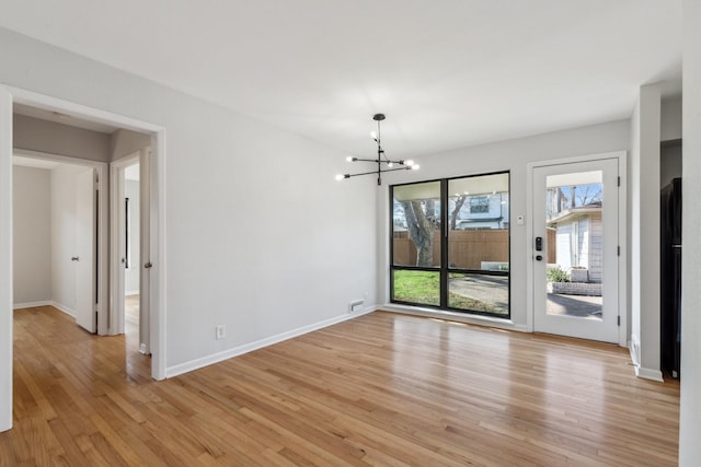 unfurnished dining area featuring an inviting chandelier and light hardwood / wood-style floors