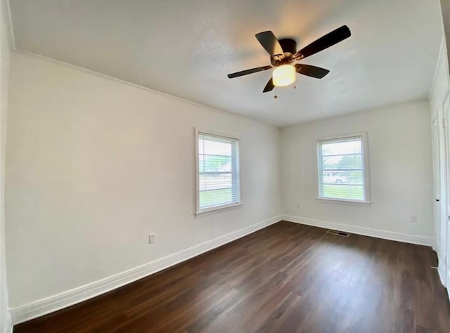 empty room featuring dark hardwood / wood-style floors, a wealth of natural light, and ceiling fan