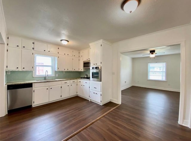 kitchen featuring sink, stainless steel appliances, a wealth of natural light, white cabinets, and dark hardwood / wood-style flooring