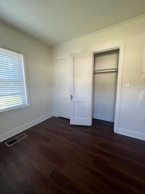 unfurnished bedroom with dark wood-type flooring and a closet