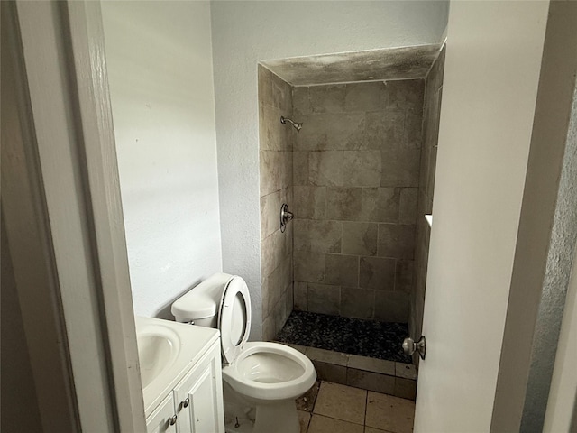 bathroom featuring tile patterned flooring, vanity, toilet, and tiled shower