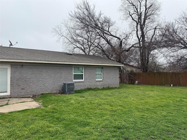 view of side of home with central AC unit and a yard