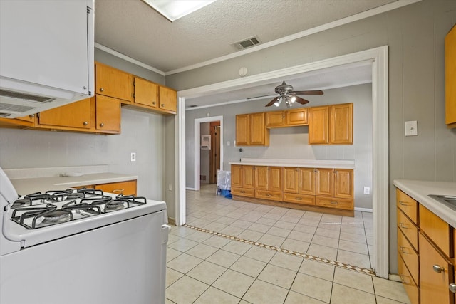 kitchen with light tile patterned floors, ceiling fan, crown molding, white gas stove, and a textured ceiling