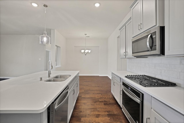 kitchen with sink, stainless steel appliances, dark hardwood / wood-style floors, an island with sink, and decorative light fixtures