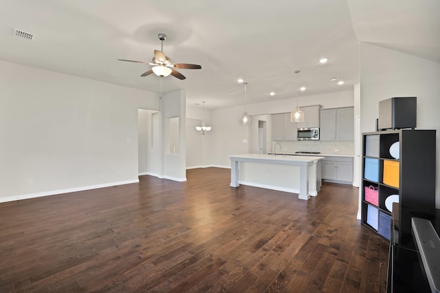 unfurnished living room with sink, dark hardwood / wood-style floors, and ceiling fan with notable chandelier