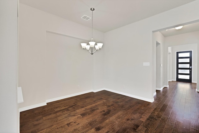 empty room featuring dark wood-type flooring and an inviting chandelier