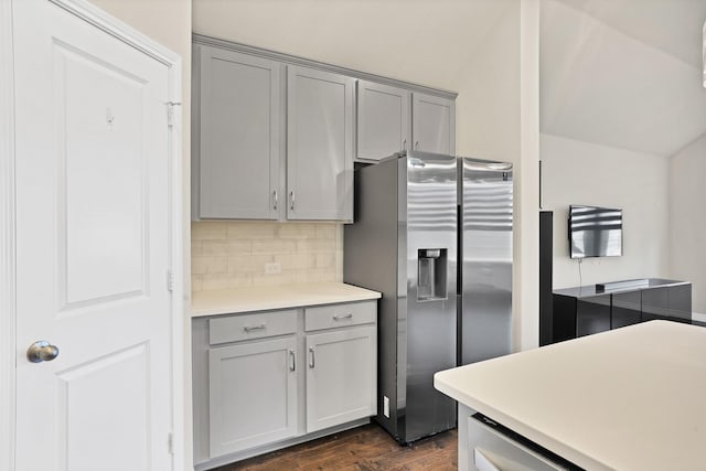 kitchen featuring dark wood-type flooring, gray cabinets, stainless steel fridge with ice dispenser, and decorative backsplash