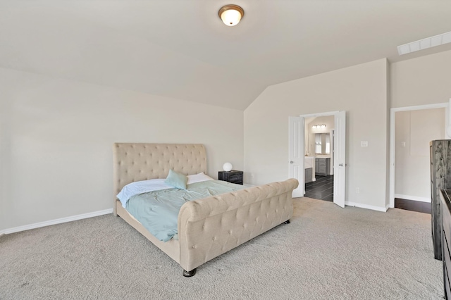 bedroom featuring ensuite bathroom, vaulted ceiling, and carpet