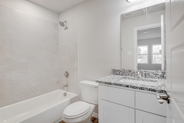 full bathroom with tiled shower / bath, vanity, and toilet