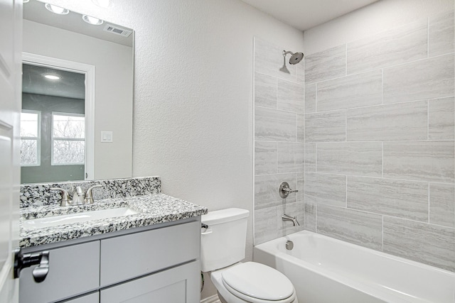 full bathroom with vanity, tiled shower / bath combo, and toilet