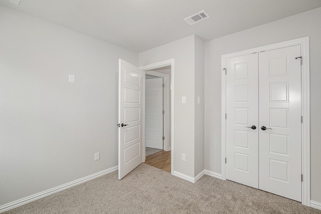 unfurnished bedroom featuring light carpet and a closet