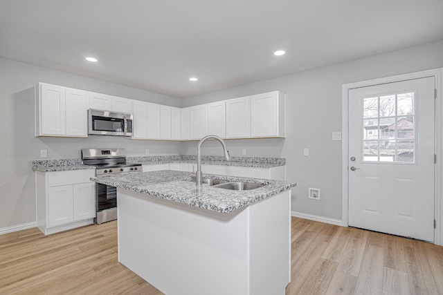 kitchen featuring sink, stainless steel appliances, an island with sink, and white cabinets