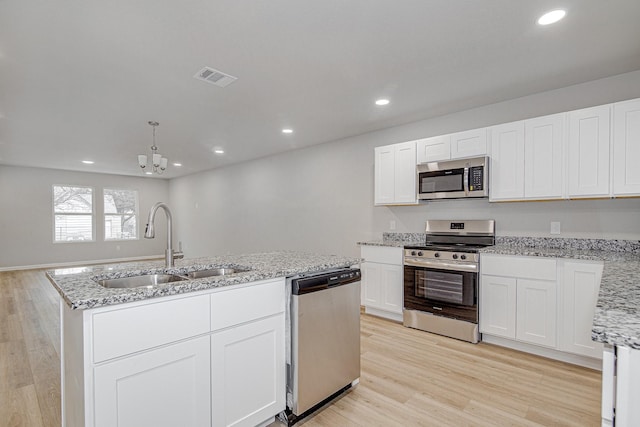 kitchen with sink, an island with sink, stainless steel appliances, light hardwood / wood-style floors, and white cabinets