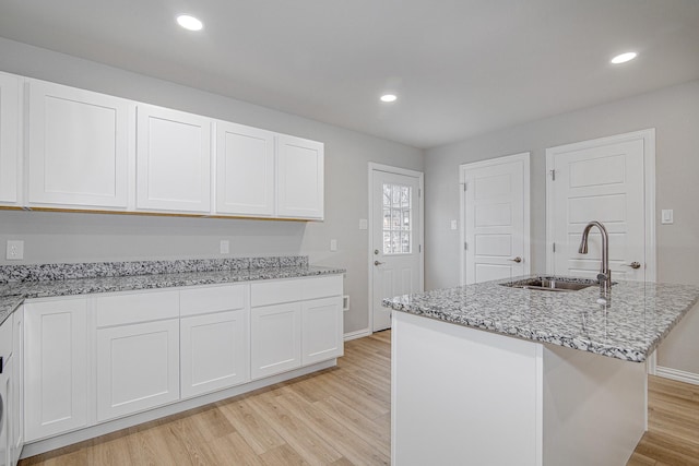 kitchen with an island with sink, sink, and white cabinets