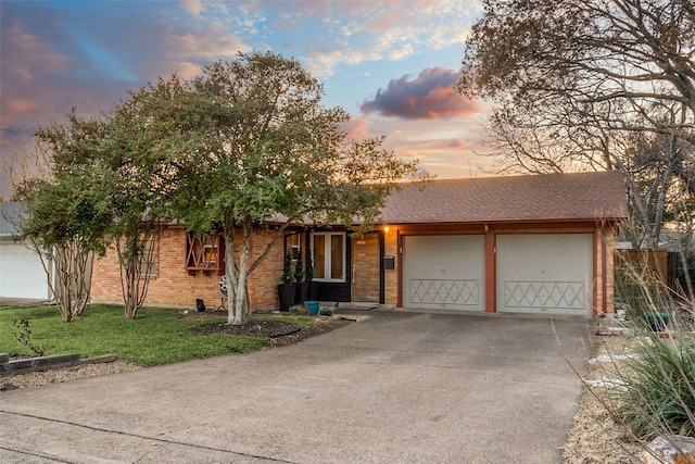 ranch-style house featuring a garage, brick siding, driveway, and a shingled roof