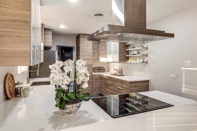 kitchen with island exhaust hood, black electric stovetop, and stainless steel fridge