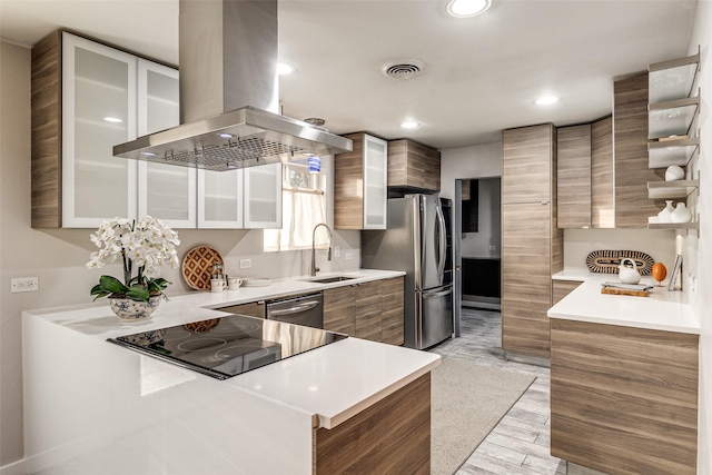 kitchen featuring appliances with stainless steel finishes, island range hood, sink, light hardwood / wood-style floors, and kitchen peninsula