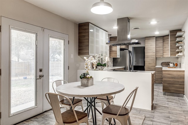 kitchen with island exhaust hood, sink, stainless steel fridge, and kitchen peninsula