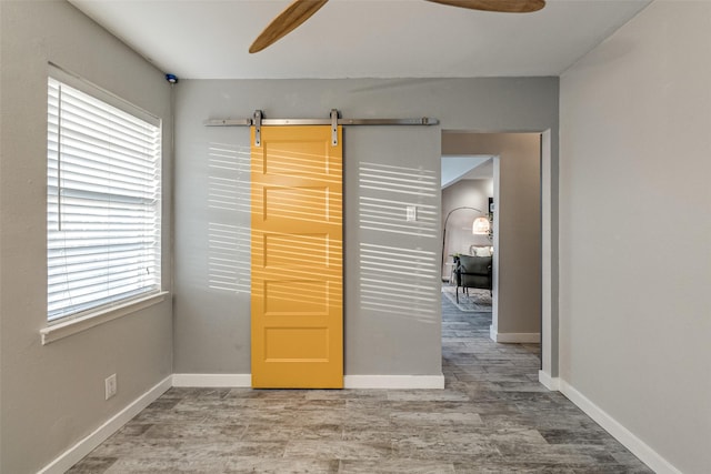 interior space featuring ceiling fan, a barn door, and hardwood / wood-style floors