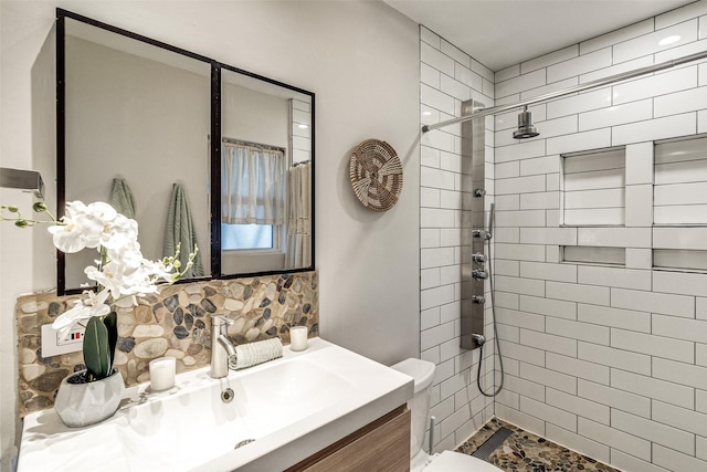 bathroom with vanity, toilet, and tiled shower