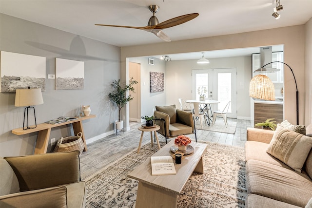 living room with french doors, ceiling fan, and light wood-type flooring