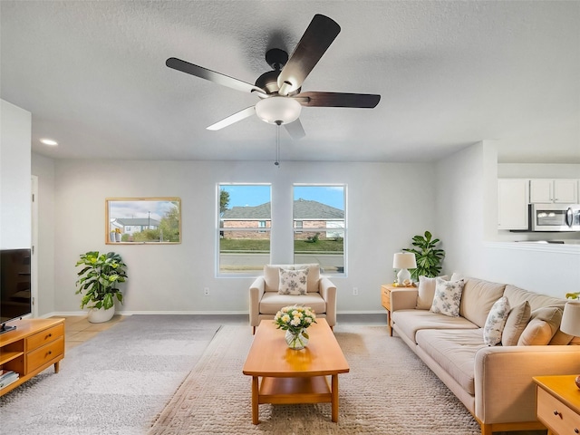 living room with light carpet, a textured ceiling, and ceiling fan