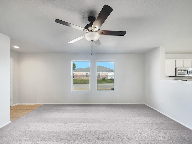 carpeted empty room with ceiling fan and a textured ceiling