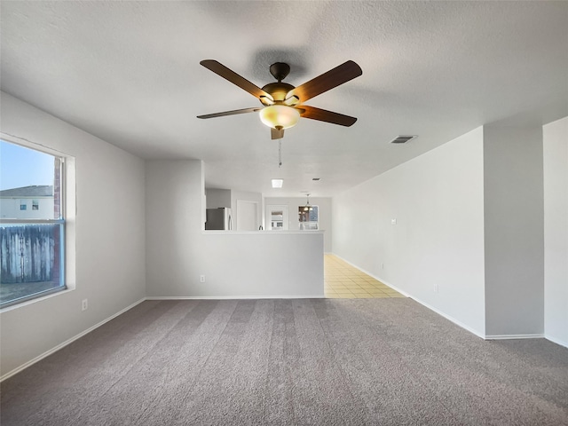 carpeted empty room featuring ceiling fan and a textured ceiling