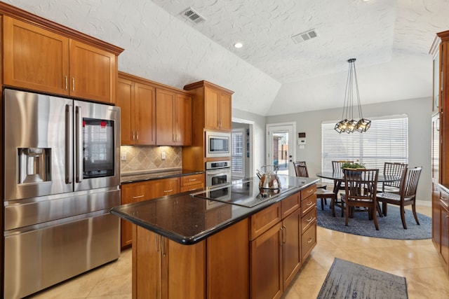 kitchen featuring decorative light fixtures, light tile patterned floors, appliances with stainless steel finishes, an island with sink, and backsplash