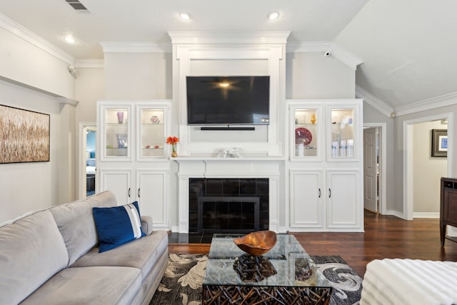 living room with crown molding, dark hardwood / wood-style flooring, a tiled fireplace, and vaulted ceiling