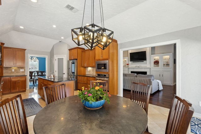 dining area featuring vaulted ceiling, a notable chandelier, and a textured ceiling