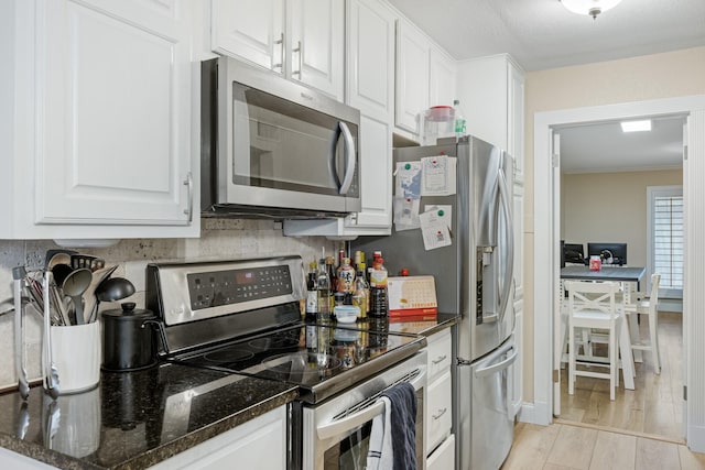 kitchen with stainless steel appliances, dark stone countertops, and white cabinets