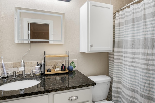 bathroom featuring vanity, tasteful backsplash, and toilet