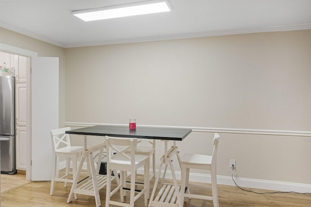 dining space with crown molding and light hardwood / wood-style flooring