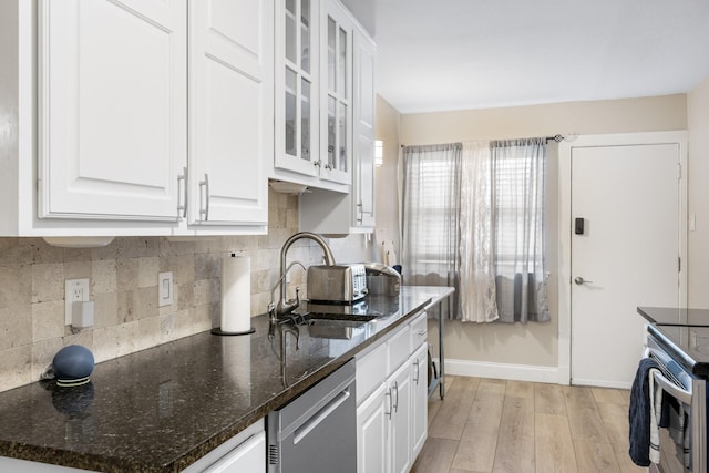 kitchen featuring sink, white cabinetry, light wood-type flooring, dishwasher, and dark stone counters