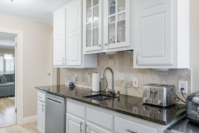 kitchen with white cabinetry, dishwasher, sink, and dark stone countertops