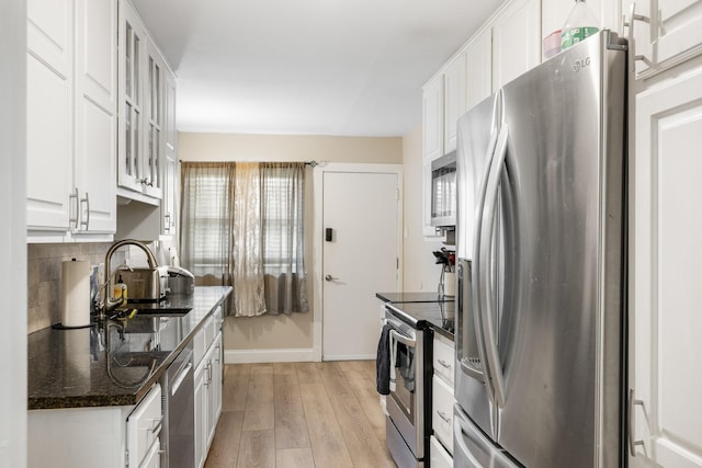 kitchen with sink, stainless steel appliances, light hardwood / wood-style floors, white cabinets, and dark stone counters