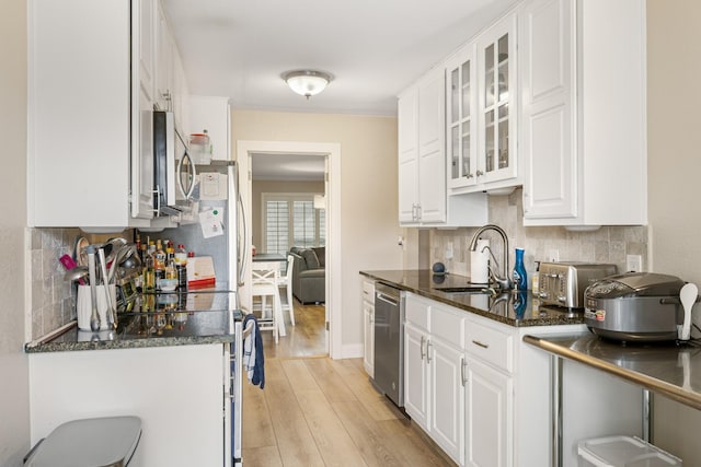 kitchen with sink, appliances with stainless steel finishes, backsplash, white cabinets, and light wood-type flooring