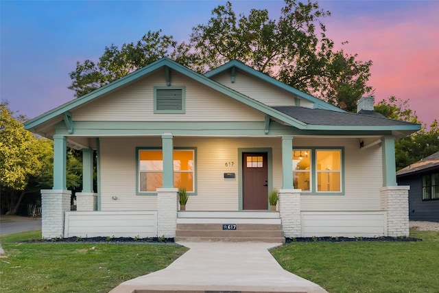 view of front of home featuring covered porch and a lawn