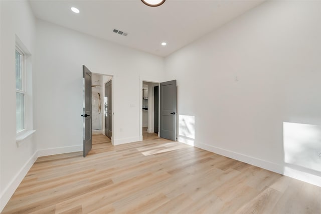 unfurnished bedroom with a walk in closet and light hardwood / wood-style floors