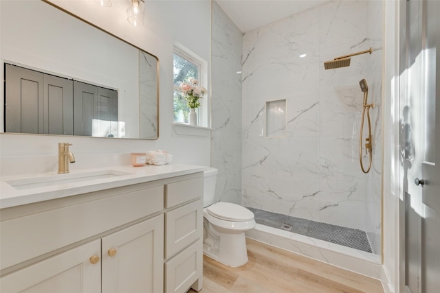 bathroom with tiled shower, vanity, toilet, and hardwood / wood-style floors