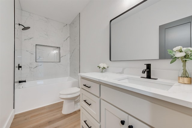 full bathroom with vanity, hardwood / wood-style floors, toilet, and tiled shower / bath