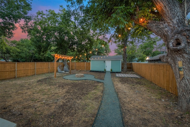 yard at dusk featuring a storage unit and an outdoor fire pit