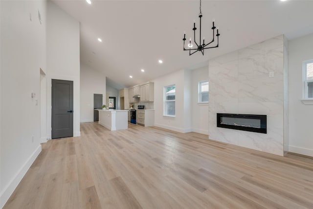 unfurnished living room featuring an inviting chandelier, a high end fireplace, heating unit, and light wood-type flooring