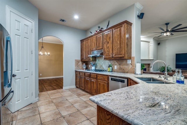 kitchen featuring sink, appliances with stainless steel finishes, kitchen peninsula, light stone countertops, and decorative backsplash