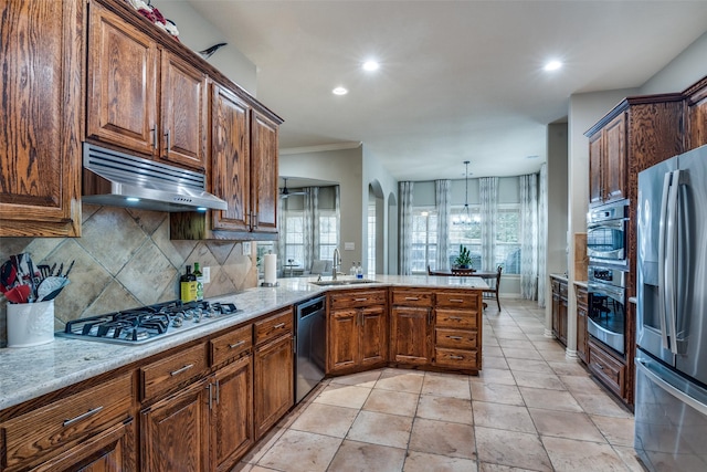 kitchen featuring appliances with stainless steel finishes, decorative light fixtures, sink, backsplash, and kitchen peninsula