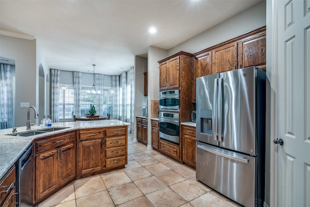 kitchen featuring pendant lighting, sink, appliances with stainless steel finishes, light stone counters, and light tile patterned flooring