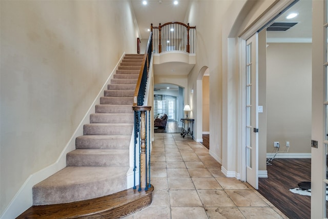 foyer entrance with crown molding, a towering ceiling, and light tile patterned flooring