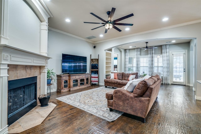 living room featuring hardwood / wood-style flooring, ornamental molding, ceiling fan, and a tile fireplace