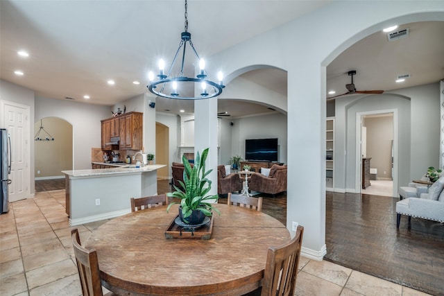 dining area with sink and ceiling fan with notable chandelier